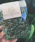 A clear packaging containing dried herbal tea leaves with a label reading 'Green Vitality Tea Blend' by Xalish Medicine.