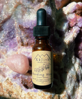 A small bottle labeled 'Bleeding Heart' by Xalish Medicine, set against a backdrop of rocks and crystals.