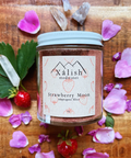 A jar of Strawberry Moon Adaptogenic Elixir by Xéalish Medicines, surrounded by strawberries, rose petals, and a crystal.