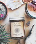 A jar of 'Xalish medicine cosmic beauty' adaptogenic longevity elixir surrounded by various plants and a cactus, suggesting a connection to nature and wellness.