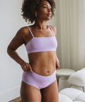 Woman wearing a light purple bikini set in a room with neutral decor.