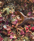 Tea leaves with a wooden spoon in a pile of colorful dried tea leaves