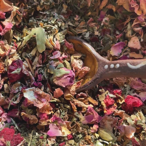 Tea leaves with a wooden spoon in a pile of colorful dried tea leaves