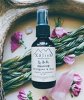 Xalish Sweetgrass & Rose energy cleansing spray bottle on a natural background with flowers and herbs.