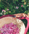 Person holding a woven basket with pink flowers against a green floral background