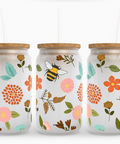 Three glass jars with floral and bee designs on a white background