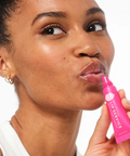 Woman applying pink lip balm labeled 'Lip Service' to her lips.