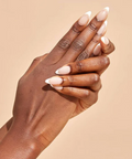 Close-up of a hand with beige nail polish on a beige background