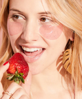 Woman holding a strawberry against a pink background