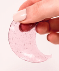 Hand holding a pink crescent-shaped object with bubbles on a white background