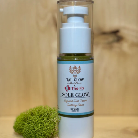 Skincare bottle labeled 'Sole Glow' on a wooden surface with a small green plant.