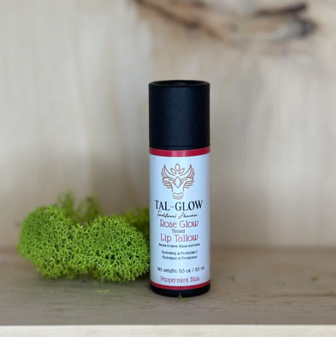 Lip balm container with 'Tal-Glow' branding on a wooden surface with a blurred natural background