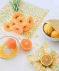 Fruits and a juicer on a table with floral-patterned wrap.