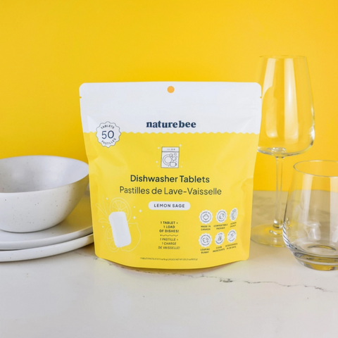 Packaging of naturebee dishwasher tablets on a kitchen counter with dishes in the background.