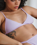 Woman wearing a light purple bra and panties set against a neutral background