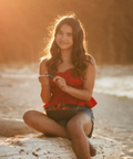 Woman sitting on a log by the beach with a blurred forest background