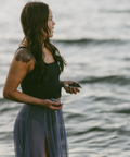 Woman standing by a body of water holding a small object