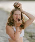 Woman applying makeup outdoors by a lake