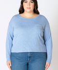 Woman wearing a light blue sweater and jeans on a white background