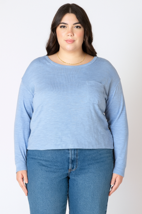Woman wearing a light blue sweater and jeans on a white background