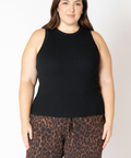 Woman wearing a black sleeveless top and leopard print pants on a white background