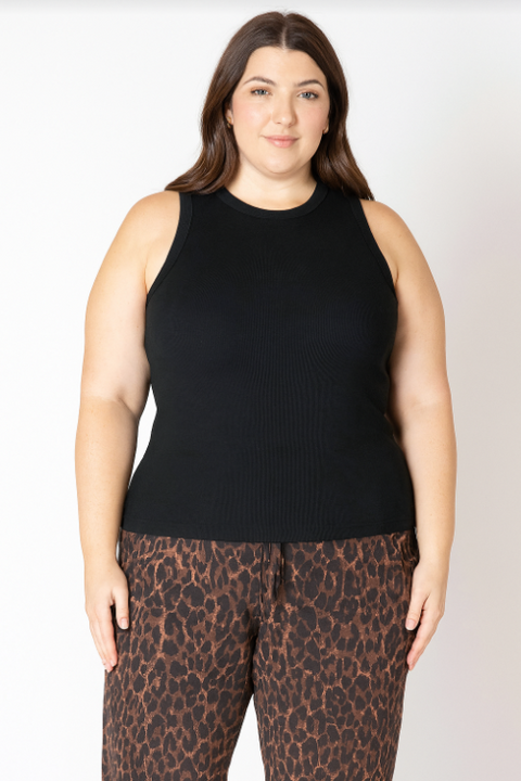 Woman wearing a black sleeveless top and leopard print pants on a white background