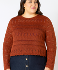 Woman wearing a brown knitted sweater and dark blue skirt on a plain background