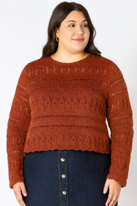 Woman wearing a brown knitted sweater and dark blue skirt on a plain background