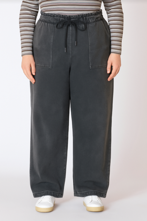 Person wearing dark gray wide-leg pants with a striped shirt on a white background