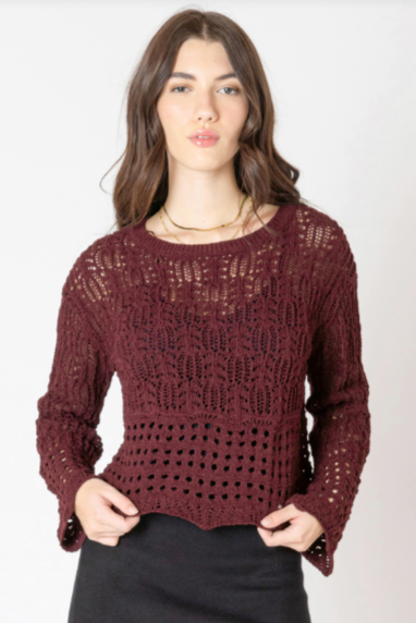Woman wearing a burgundy knitted sweater and black skirt on a white background