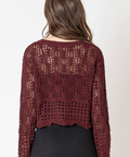 Person wearing a burgundy crochet top and black skirt on a white background