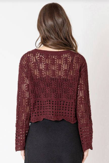 Person wearing a burgundy crochet top and black skirt on a white background