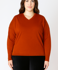 Woman wearing a rust-colored sweater against a white background