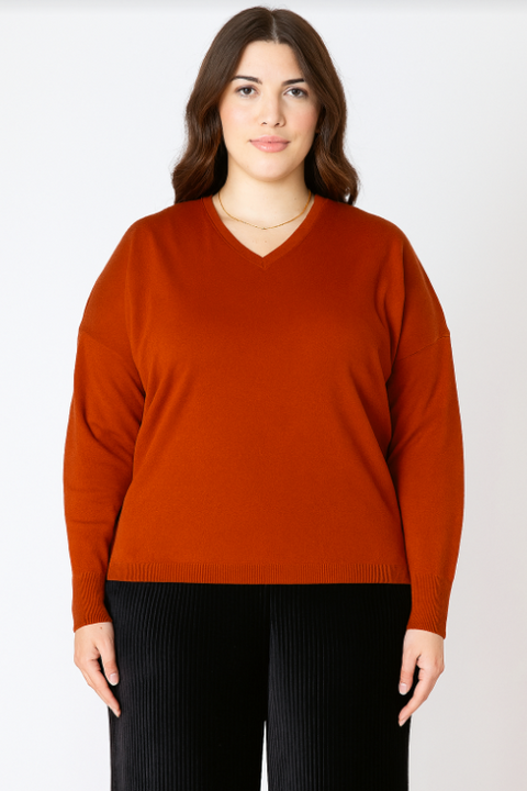 Woman wearing a rust-colored sweater against a white background