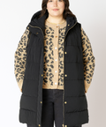 Person wearing a black puffer vest over a leopard print shirt on a white background