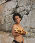Person holding flowers against a rocky background