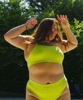 Person wearing a bright green bikini set with trees and pool in the background