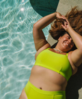 Person wearing a bright green bikini by a pool