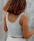 Person wearing a gray tank top against a textured wall