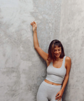Woman in gray athletic wear posing against a textured gray wall
