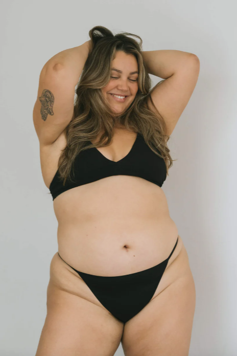 Woman wearing a black bikini against a plain background