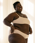 Person wearing a beige bikini set in a softly lit room.