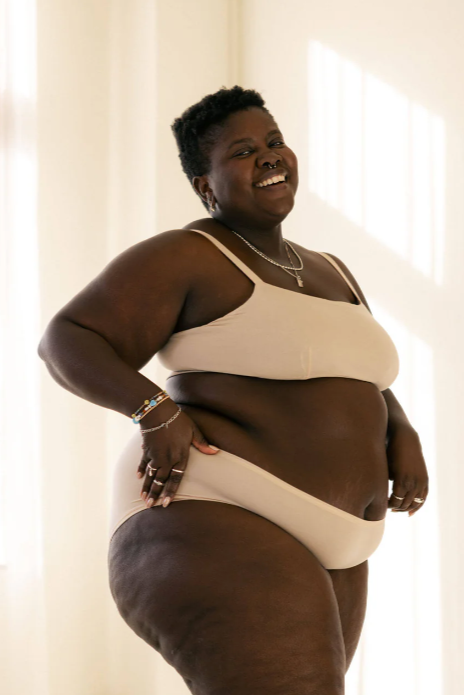 Person wearing a beige bikini set in a softly lit room.