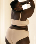 Person wearing a beige and black bodysuit against a neutral background