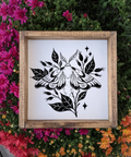 Framed black and white moth illustration on a white background, surrounded by colorful flowers.