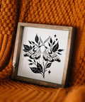 Framed black and white artwork of a moth on a textured orange surface
