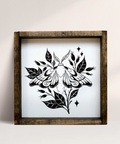 Framed artwork of a black butterfly design on a white background