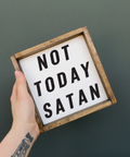 Hand holding a sign with 'Not Today Satan' text against a dark background