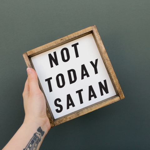Hand holding a sign with 'Not Today Satan' text against a dark background