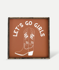 Decorative sign with cowboy boots and 'Let's Go Girls' text on a brown background